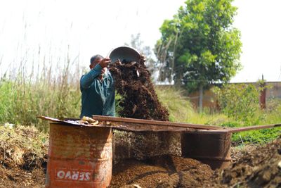 Indian gardener pouring organic compost outdoors